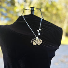 Load image into Gallery viewer, Glass necklace with a large oval pendant on a black mannequin against a blurred natural background