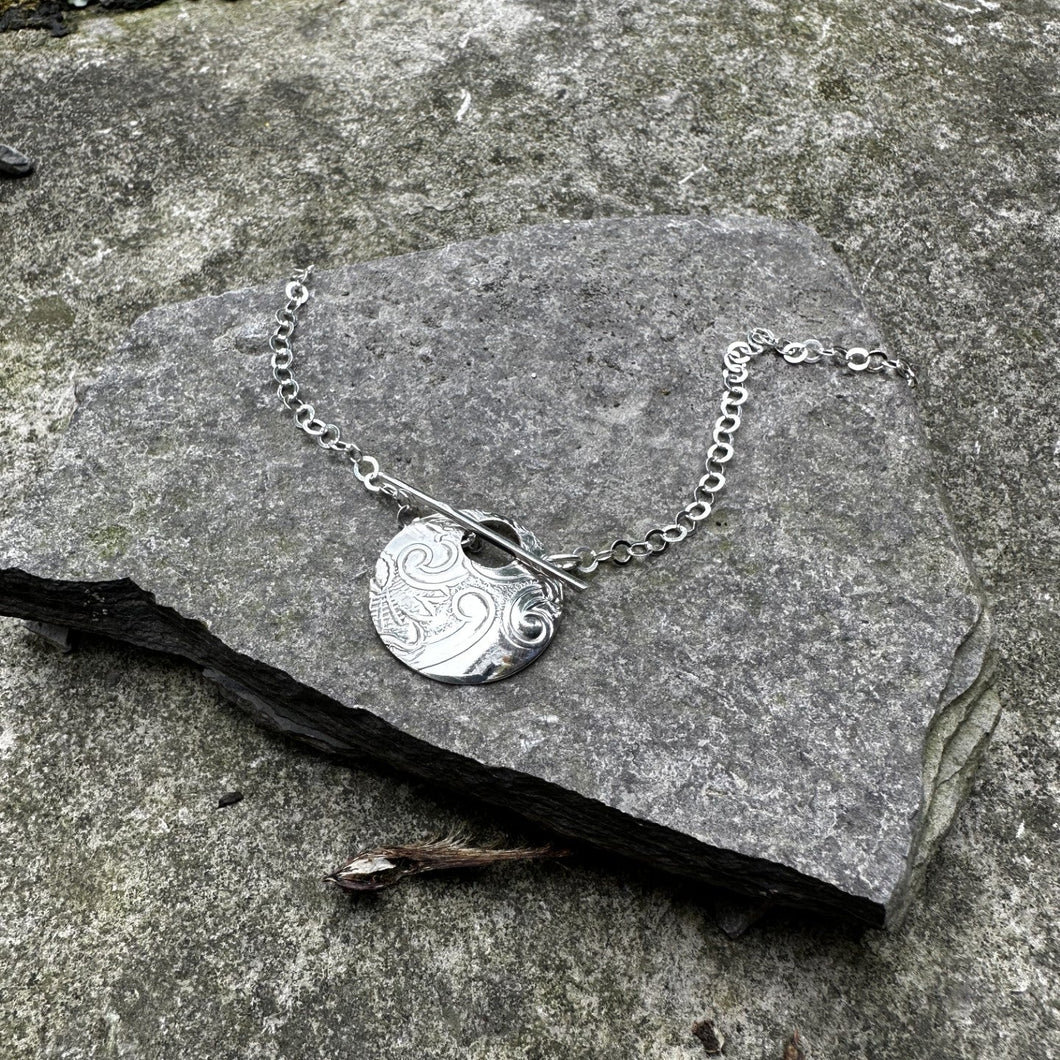 Sterling silver necklace with a round pendant on a stone surface
bread plate pendant toggle front closure recycled restyled Canadian art